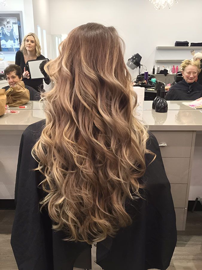 A Woman With Long Curly Hair is Sitting in a Chair in a Salon — Artistry of Hair in Redlynch, QLD