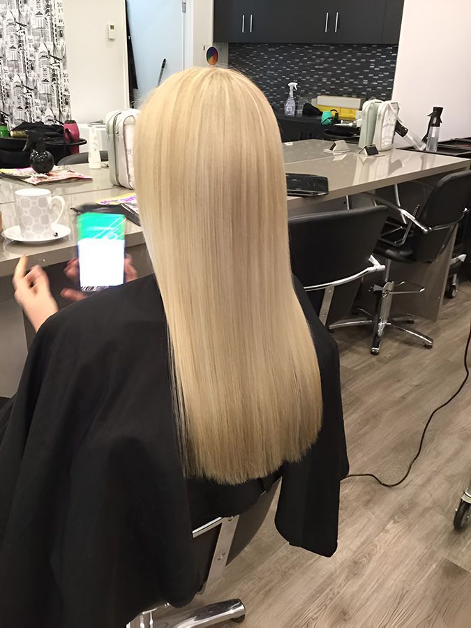 A Woman is Sitting in a Chair in a Salon Holding a Cell Phone — Artistry of Hair in Redlynch, QLD