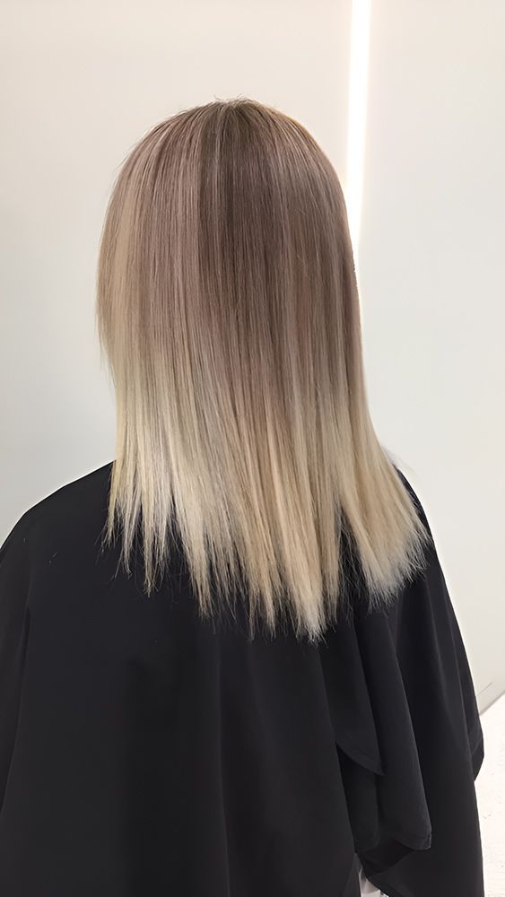 A Woman With Blonde Hair is Wearing a Black Cape — Artistry of Hair in Redlynch, QLD