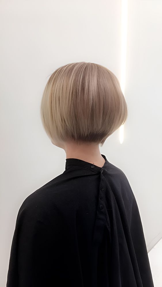 A Woman With Short Blonde Hair is Wearing a Black Cape — Artistry of Hair in Redlynch, QLD