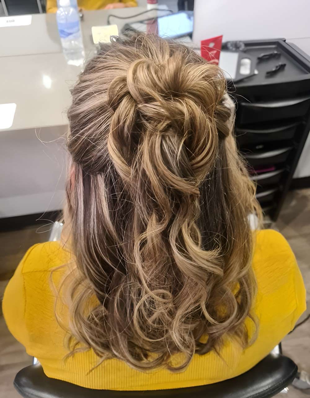 A Woman is Sitting in a Chair With Her Hair in a Bun — Artistry of Hair in Redlynch, QLD