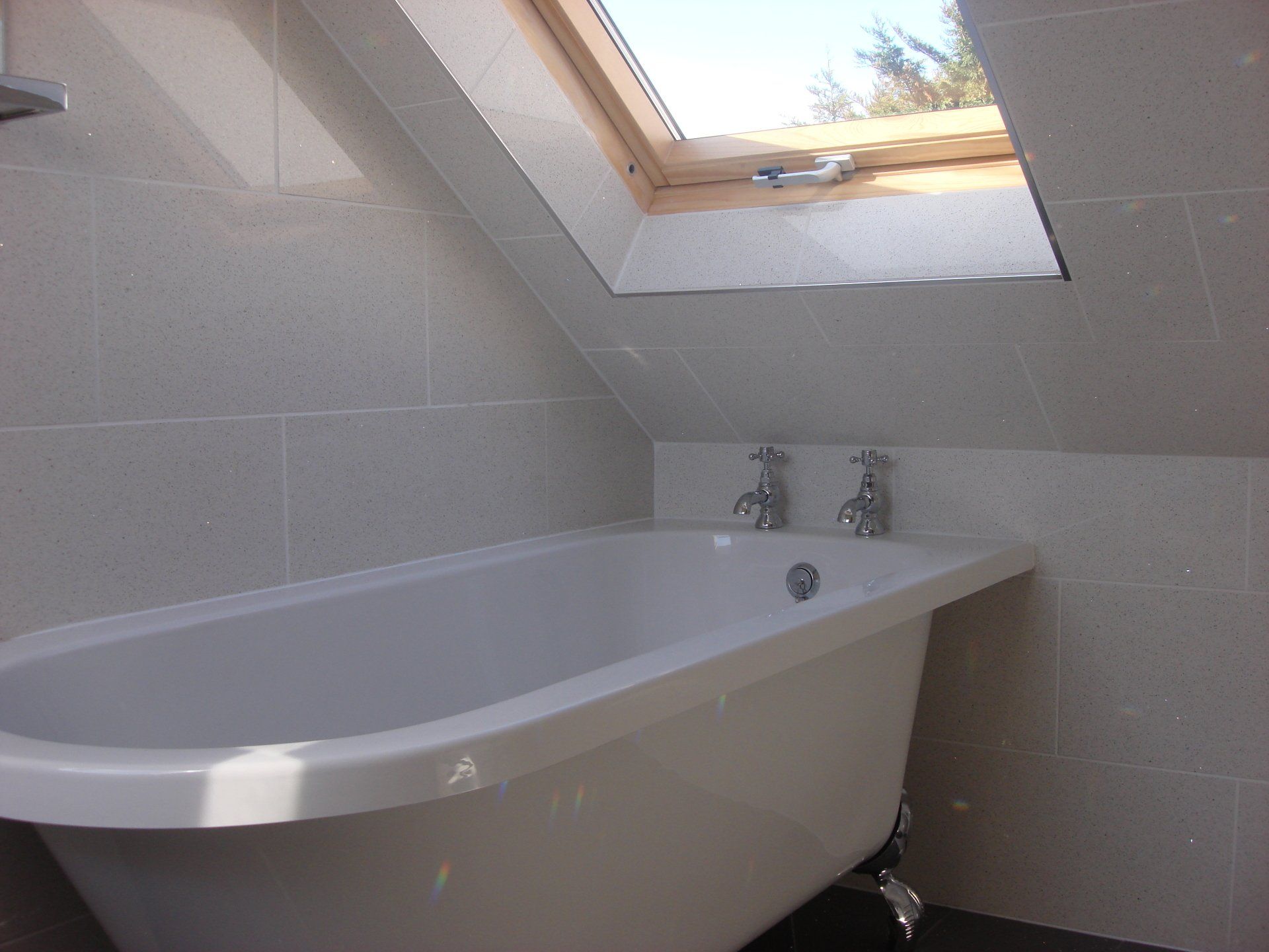 bathtub fitted under loft windows of a bathroom