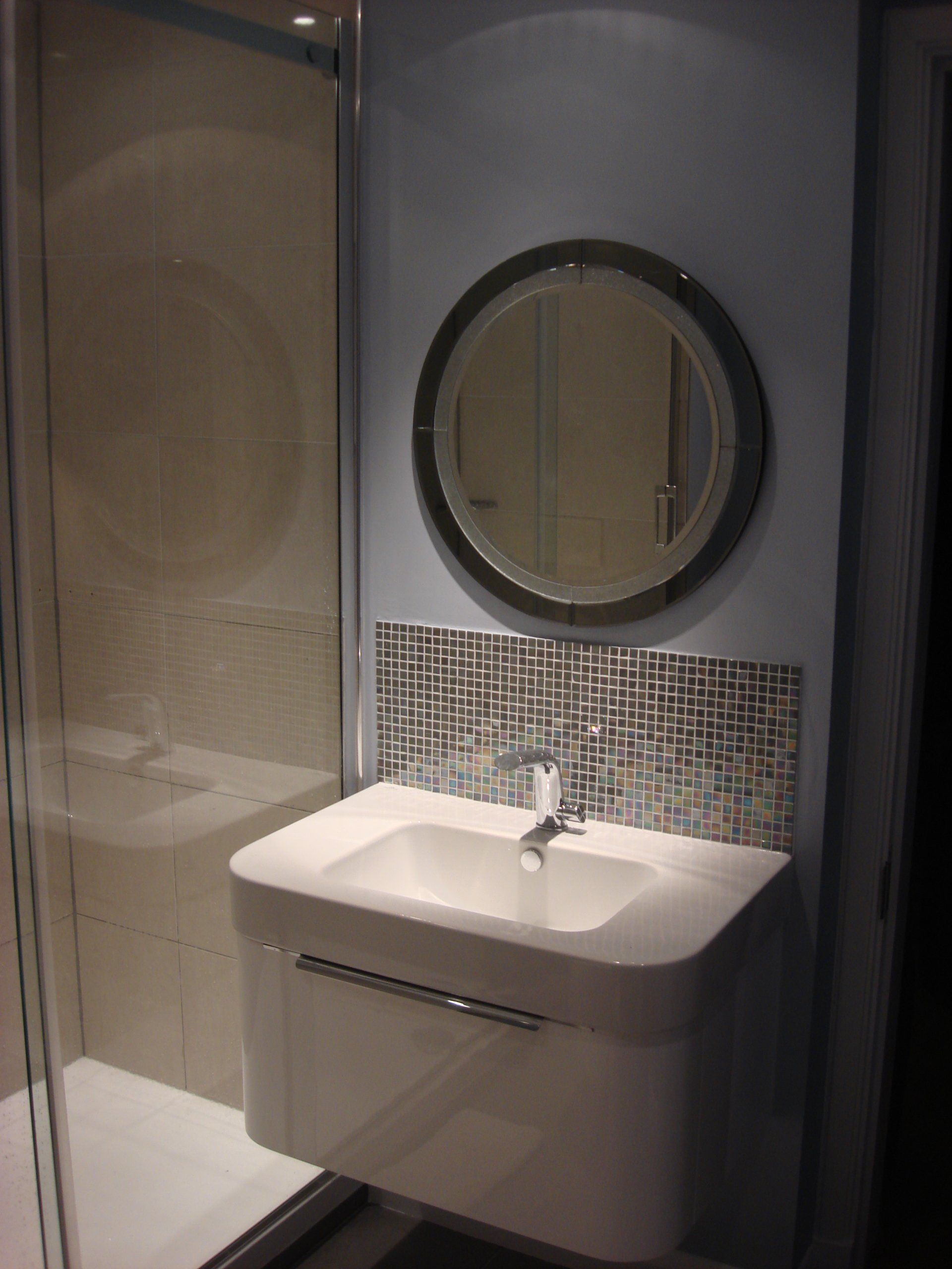 a round mirror installed above bathroom sink