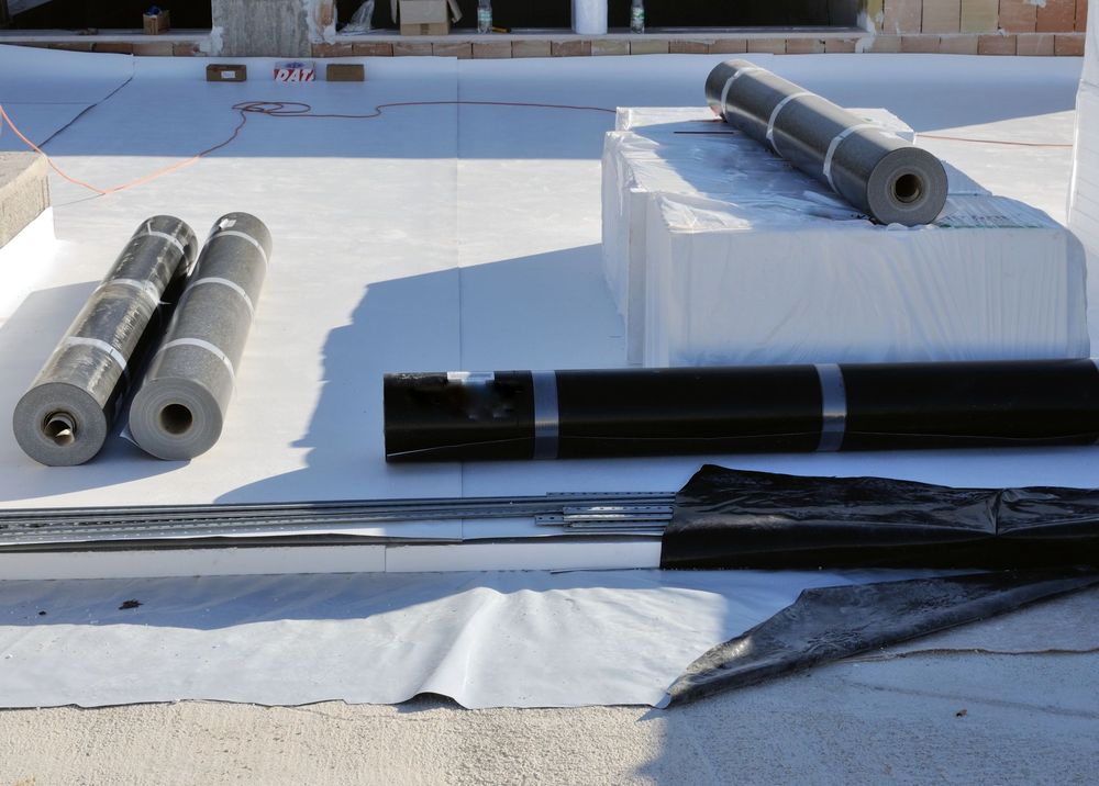 Materiali di copertura e rotoli di membrana nera e grigia disposti su un tetto piano