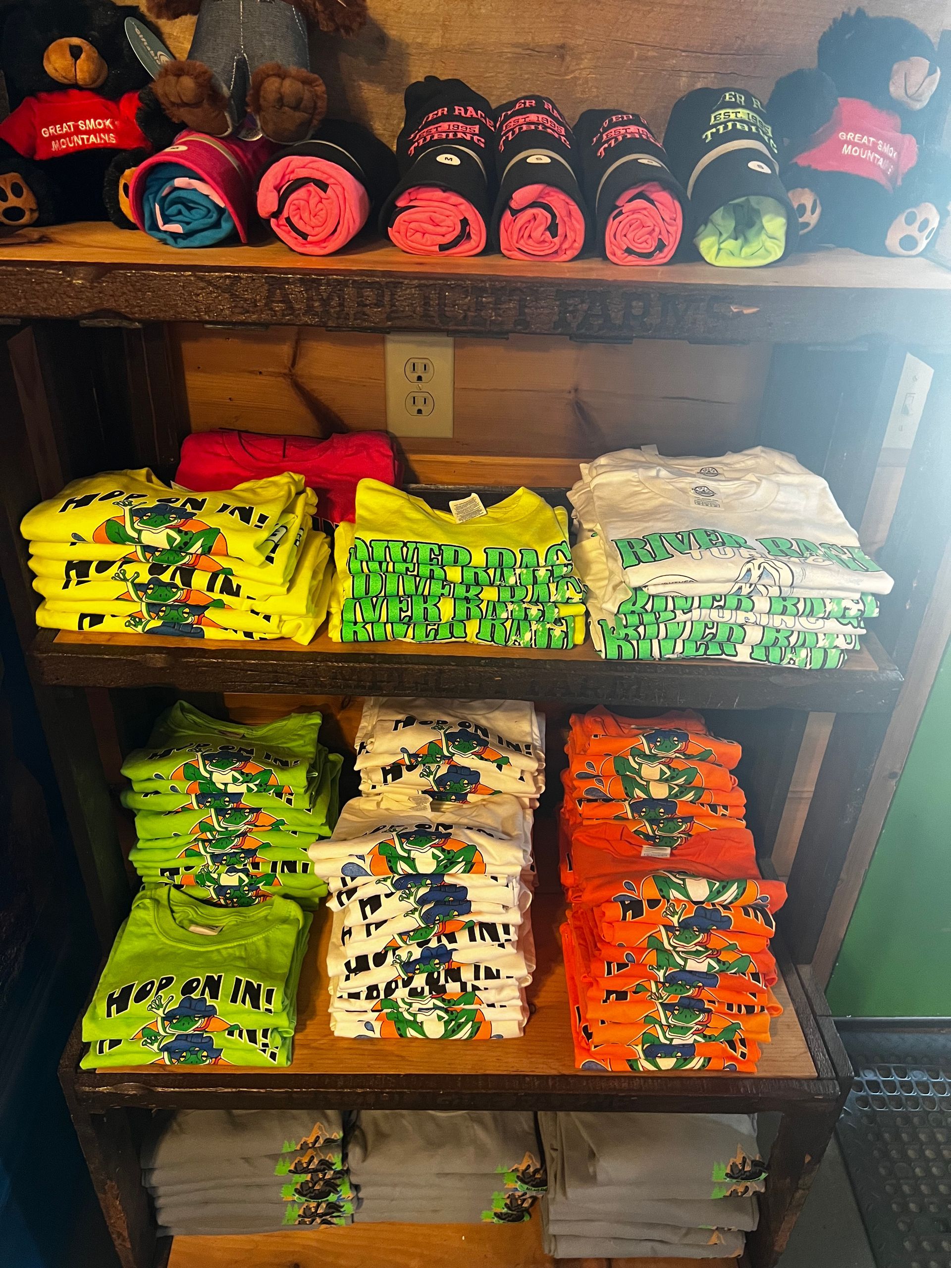 A shelf filled with a variety of t-shirts and towels