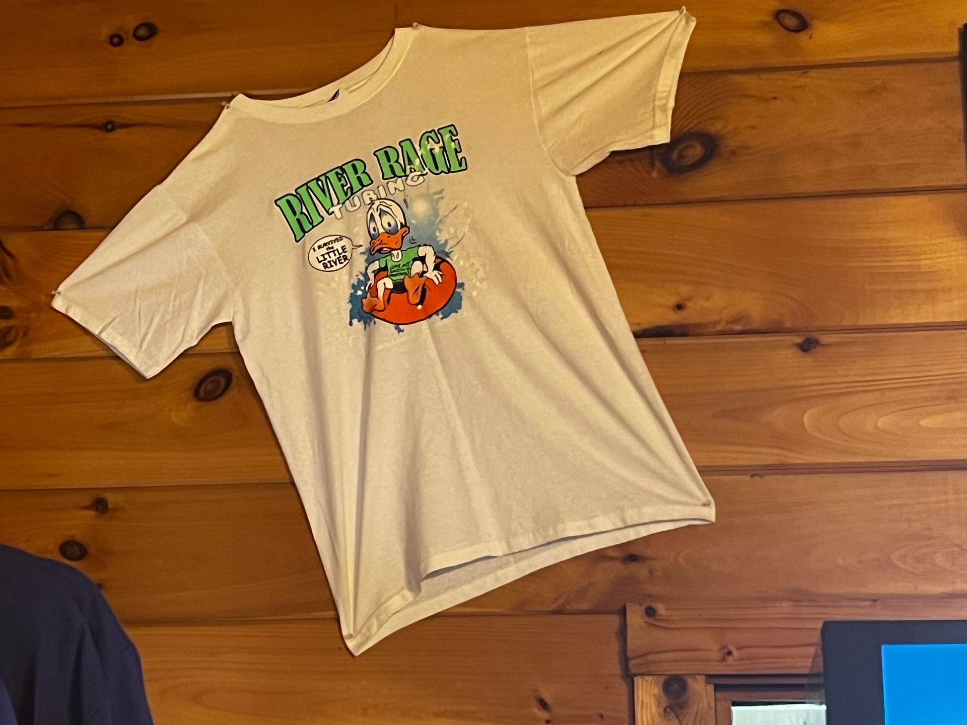 A white t-shirt is hanging on a wooden wall