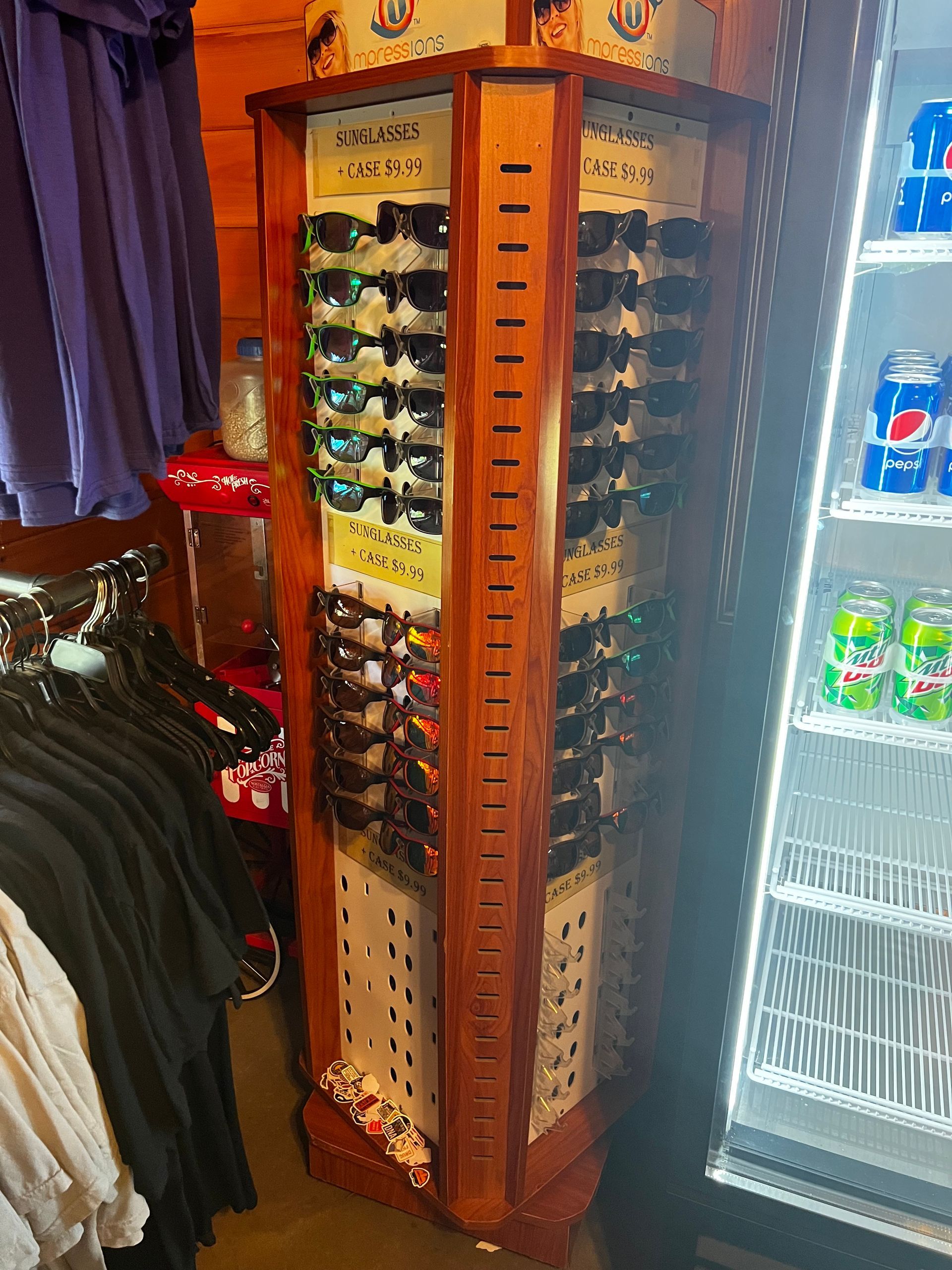 A sunglasses display in a store next to a pepsi fridge