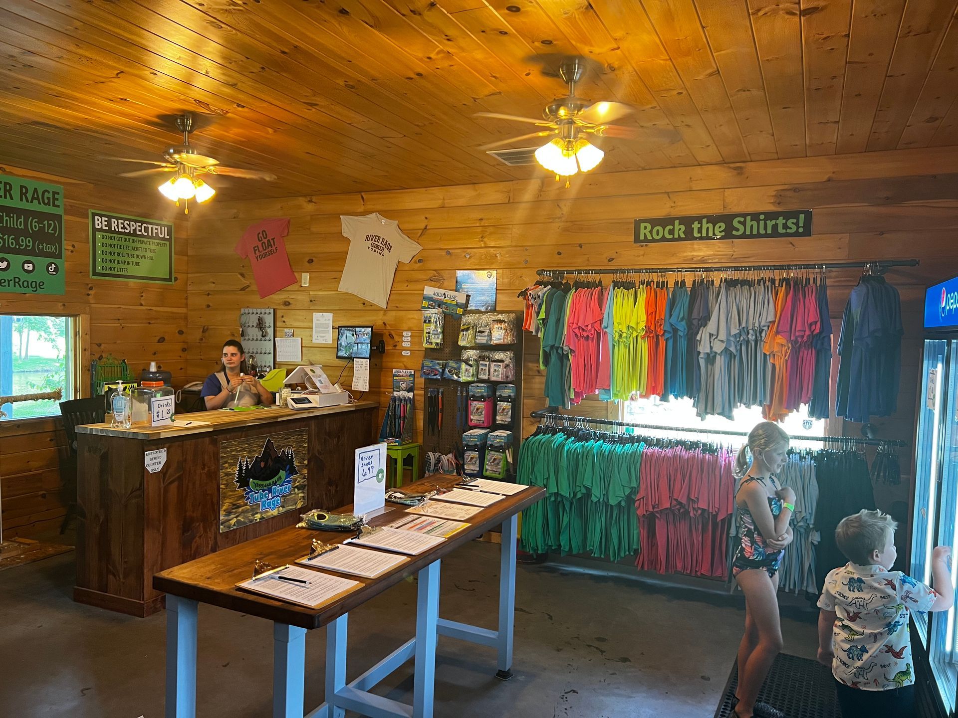 A store filled with lots of colorful shirts and a ceiling fan.