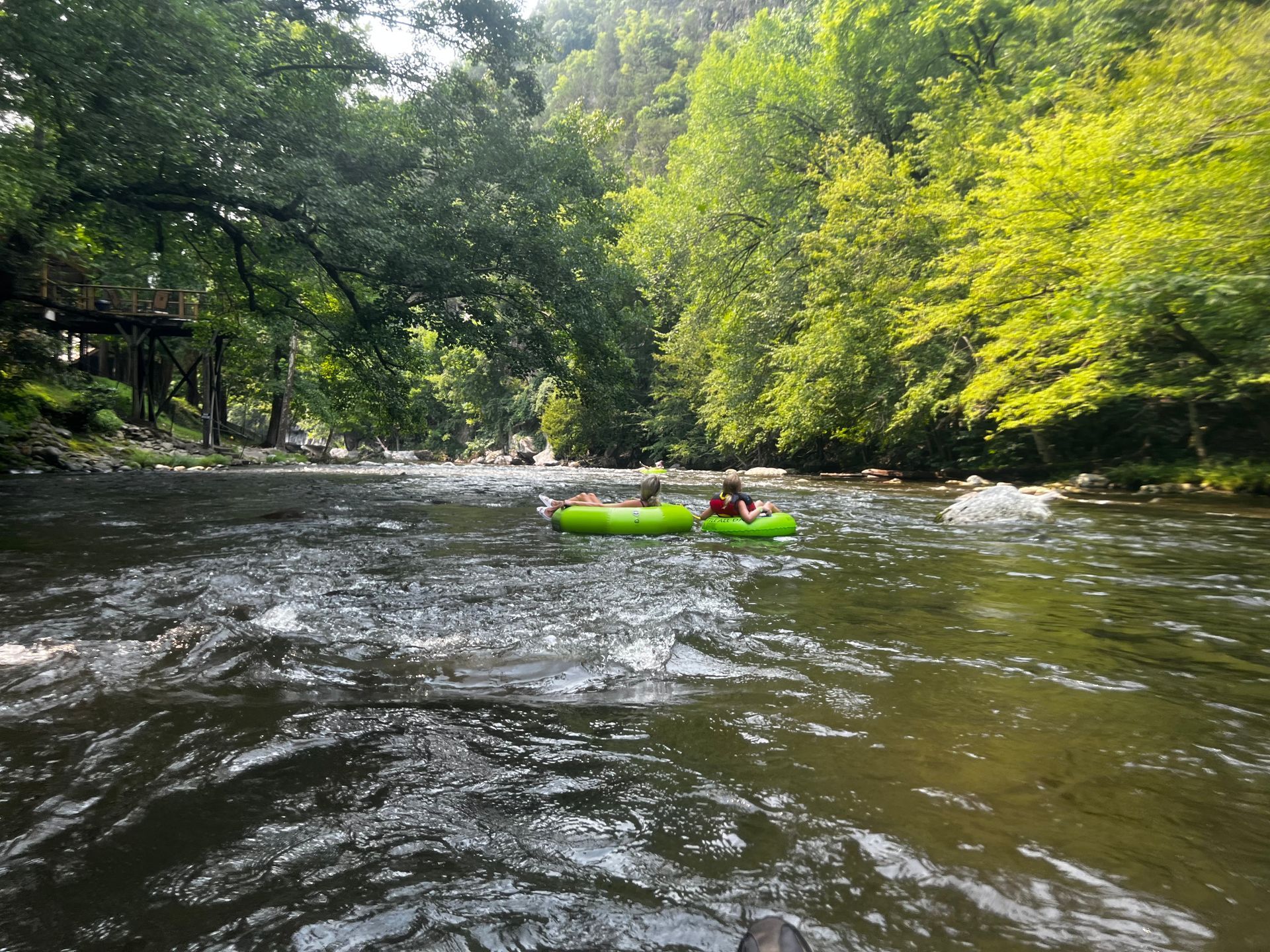 A person in a green raft is floating down a river.