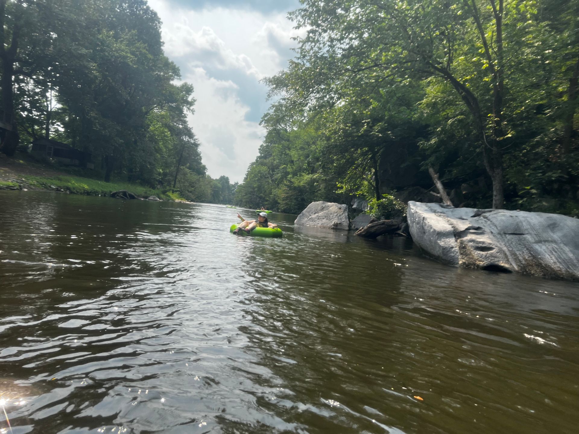 A person in a green raft is floating down a river.