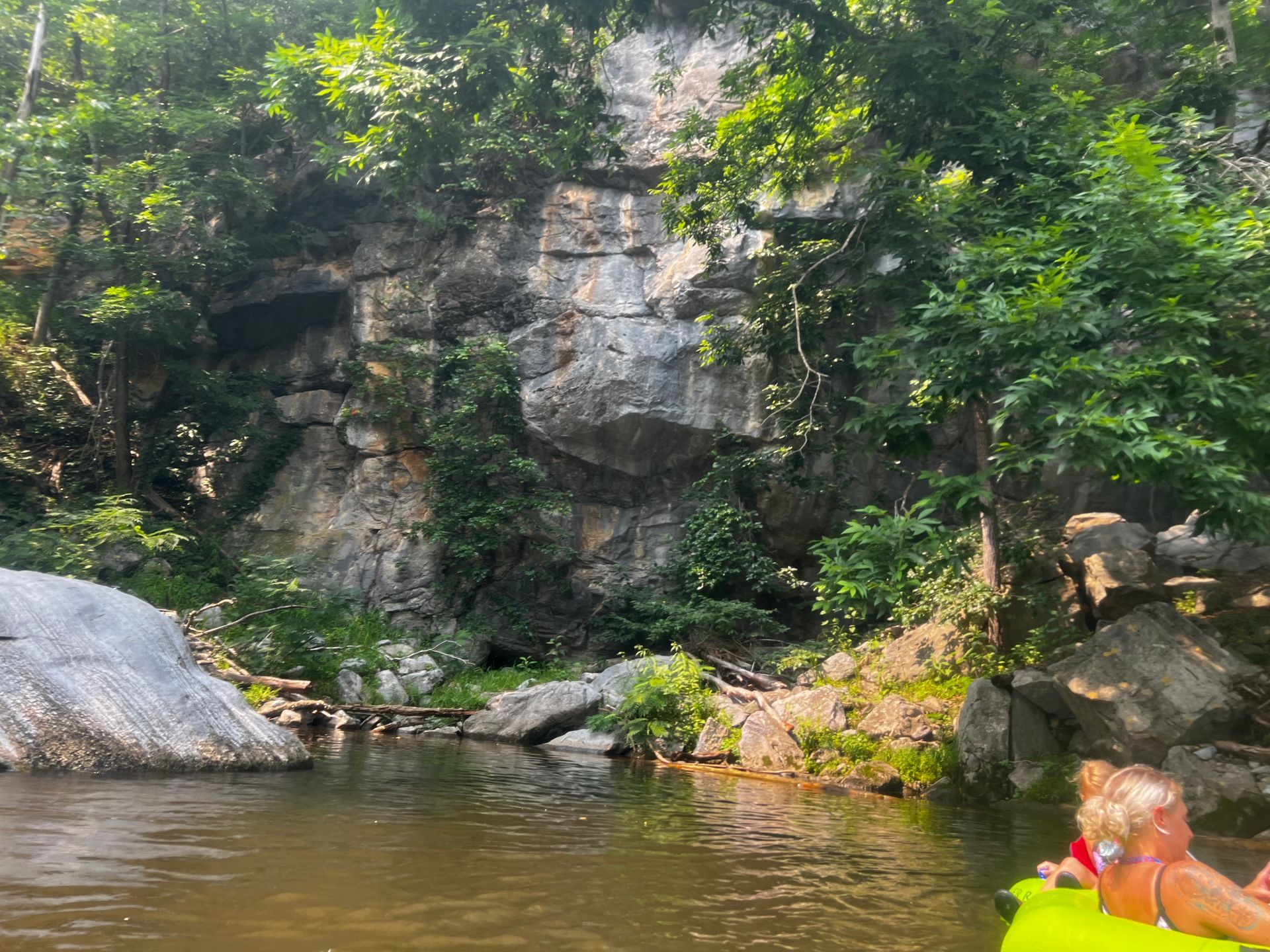 A couple of people are floating on a tube in a river.