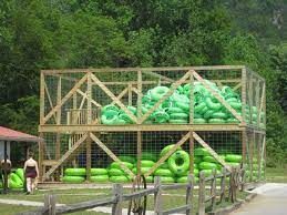A bunch of green tubes are stacked on top of each other in a cage.