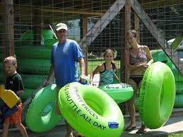 A group of people are standing next to each other holding green inner tubes.