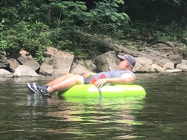 A man is laying on a green raft in the water.