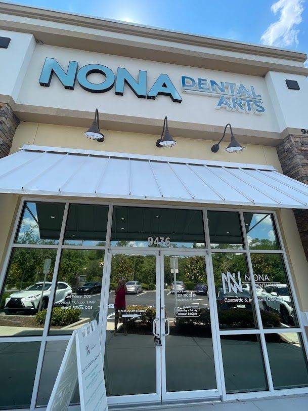 Nona Dental Arts storefront with large windows, teal sign, and a white awning.