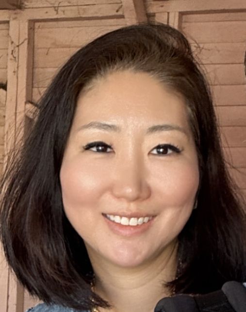 A woman with long brown hair is smiling and wearing a striped shirt