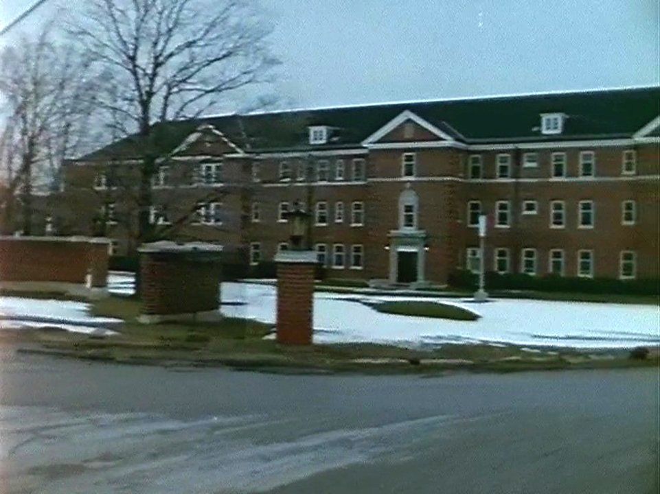 An image of Cottage O from the film Danny and Nicky. It is a large three storey red brick building with a peaked roof. It is winter time and there is snow on the ground in front of the cottage. In the 1970s, this building was the site of a venereal disease outbreak and staff were instructed to not tell residents’ parents about the incident. Policies like this helped to hide sexual abuse at the Huronia Regional Centre. Image from the National Film Board of Canada documentary Danny and Nicky.