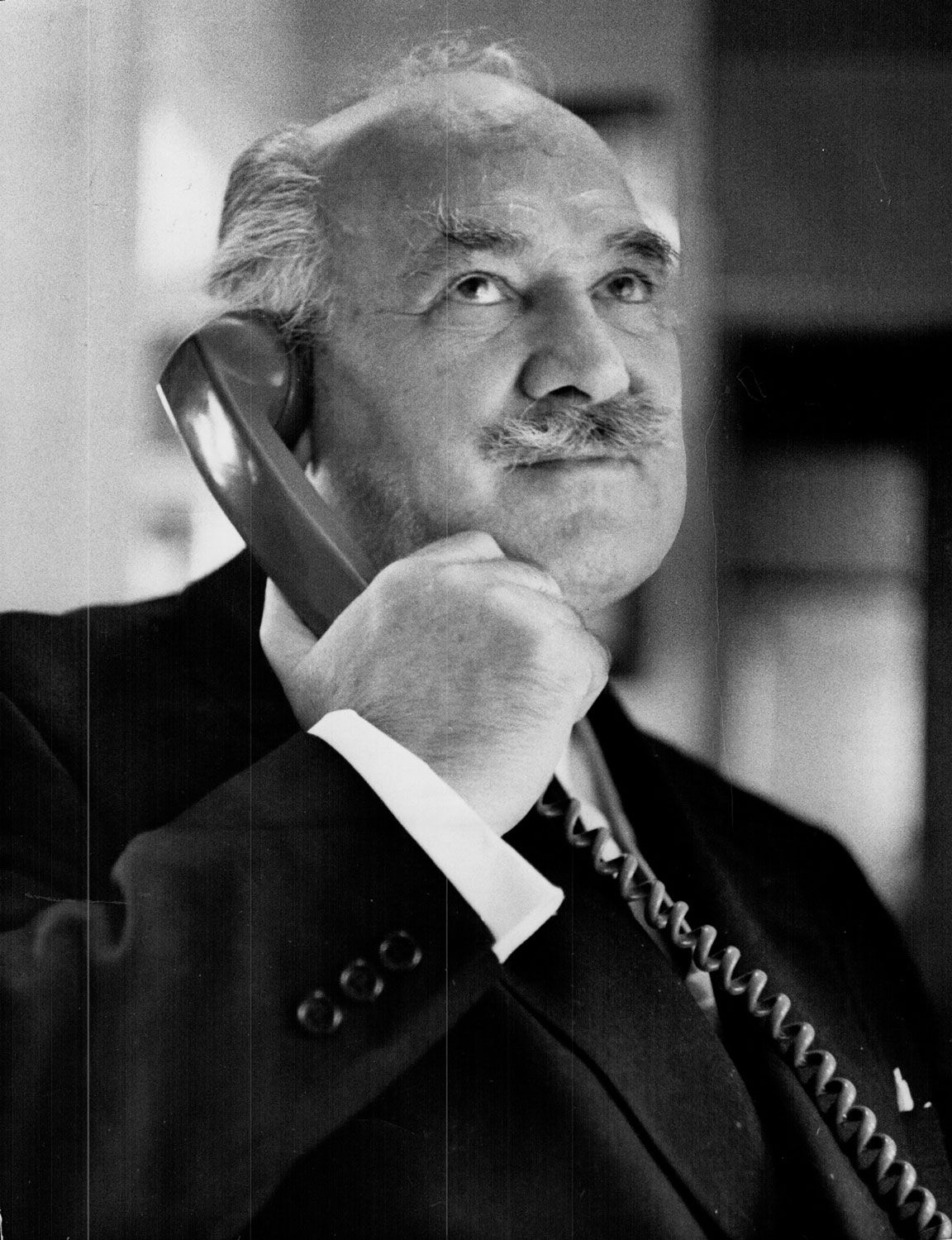David Fingard, inventor of Resperin, in 1969, one year after the experiments conducted at the Huronia Regional Centre. He is a balding man with a bushy gray mustache, wearing a black suit and holding a telephone receiver up to his ear. Image from the Toronto Star Archives.