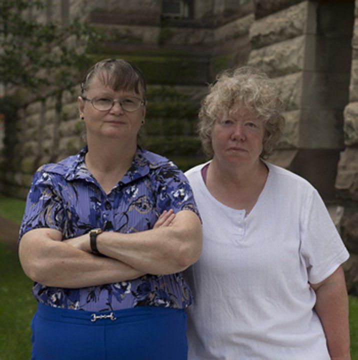 An image of Pat Seth (right) and Marie Slark (left), the two representative plaintiffs in the Huronia Regional Centre class action lawsuit. Marie is dark haired woman with oval wire-rimmed glasses and she wears blue slacks and a purple-blue button up short sleeve shirt. Pat is a woman with short curly blonde hair and she wears a white short sleeve shirt. Image from an issue of Canada’s History Magazine.