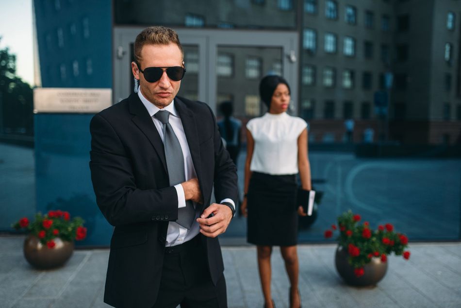 A man in a suit and tie is standing next to a woman in a white shirt.