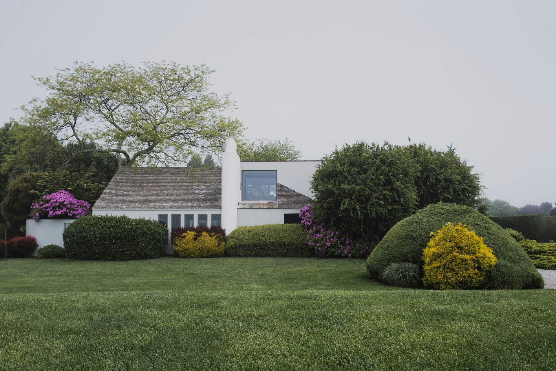 A white house with a lush green lawn in front of it