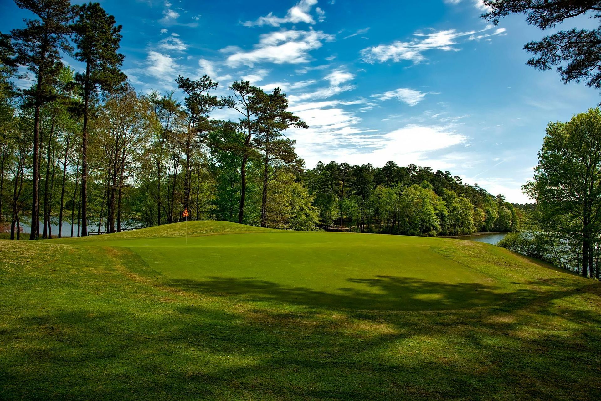 A golf course with trees and a lake in the background