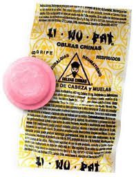 Una piruleta rosa está encima de un envoltorio amarillo.
