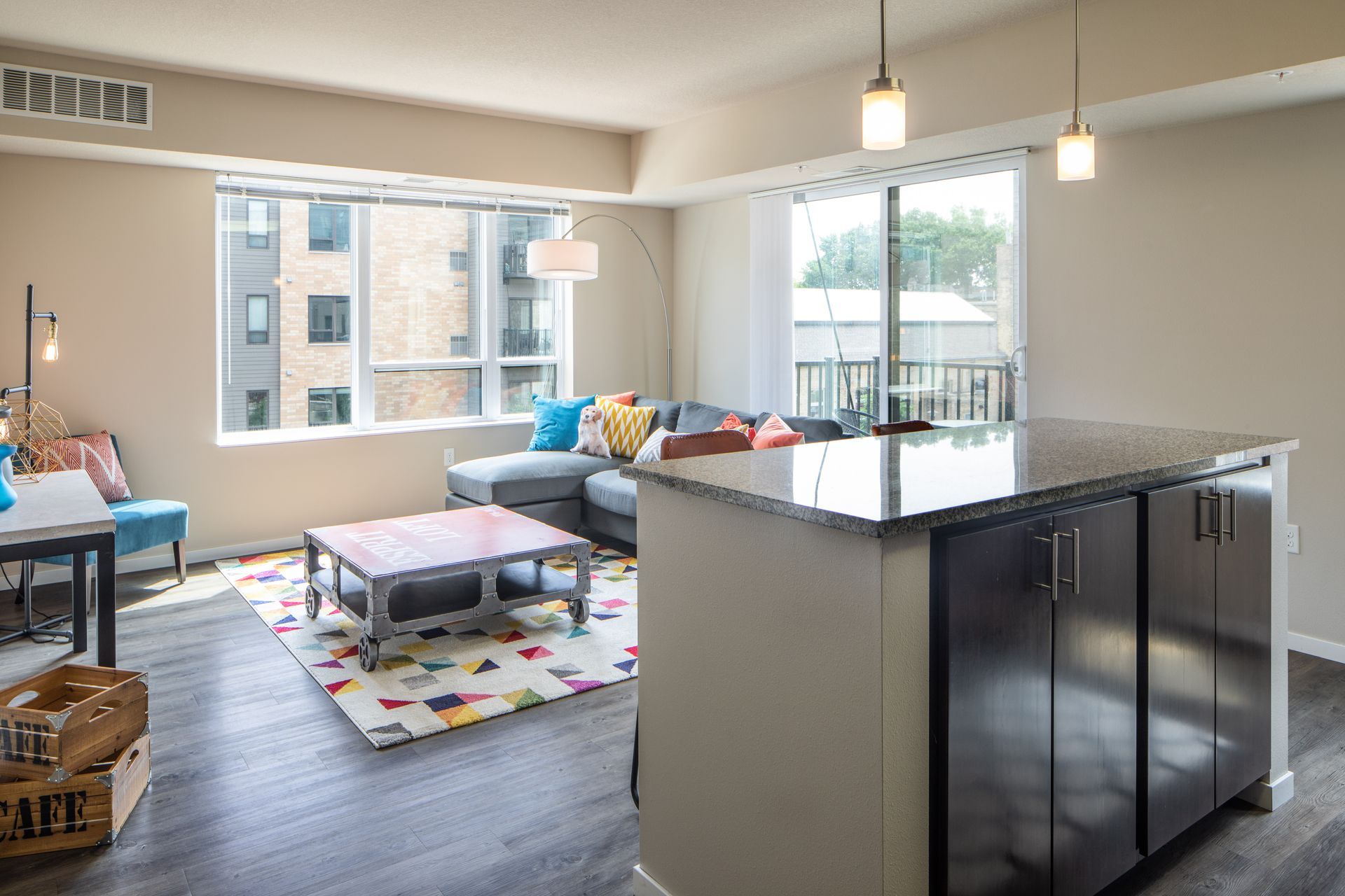 Living room with a kitchen island, sofa, window, and colorful rug.
