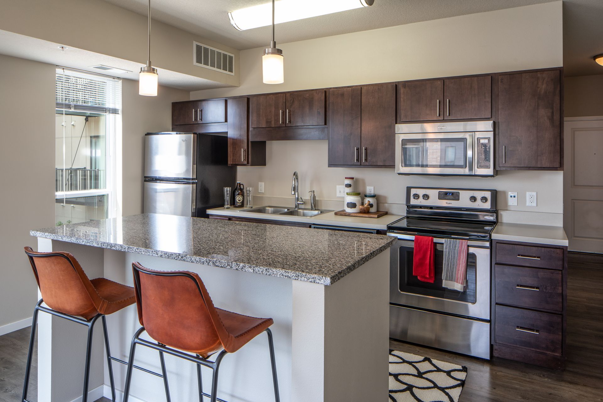 Kitchen with dark cabinets, stainless steel appliances, breakfast bar, and stools.