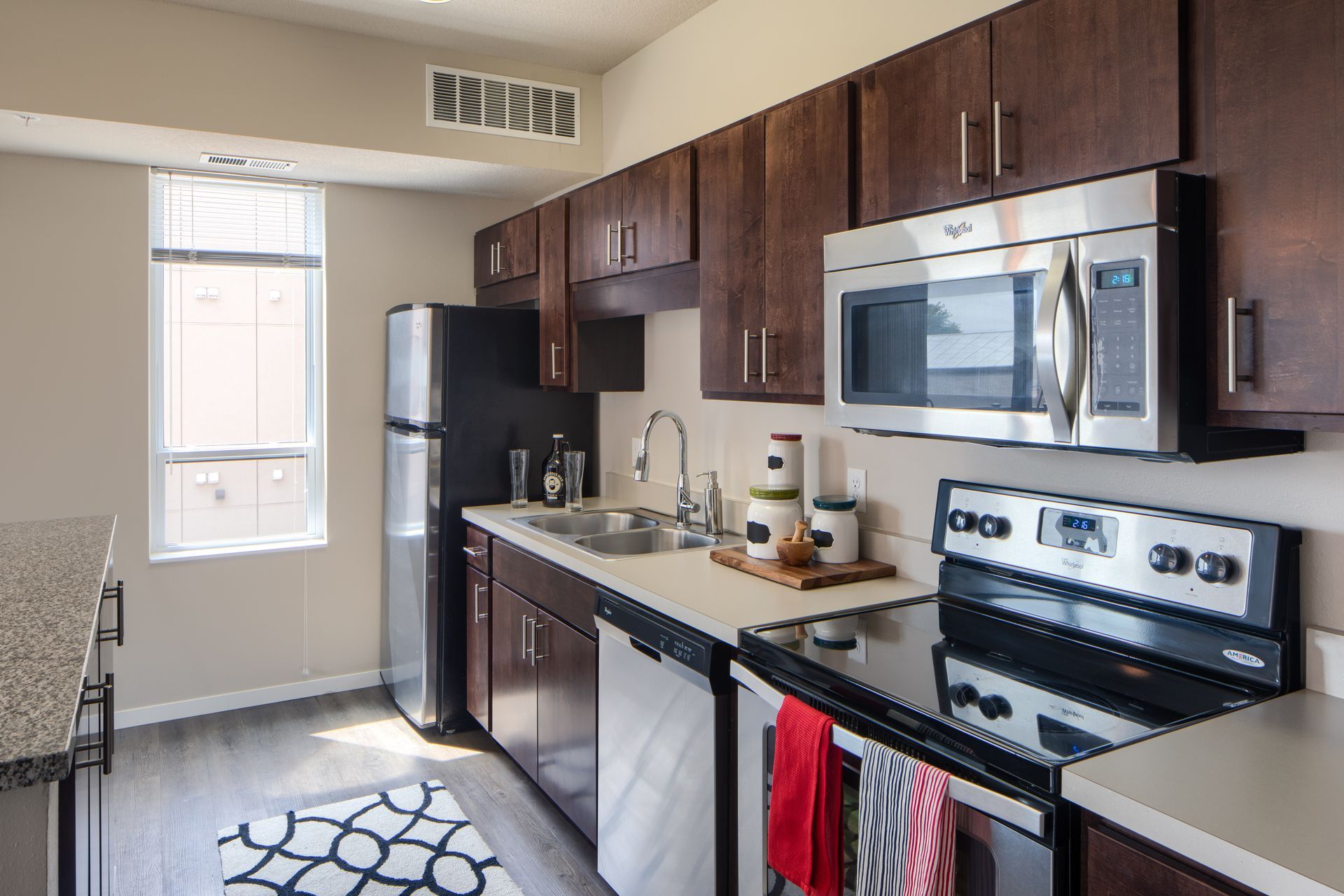 Modern kitchen with dark brown cabinets, stainless steel appliances, and a window.