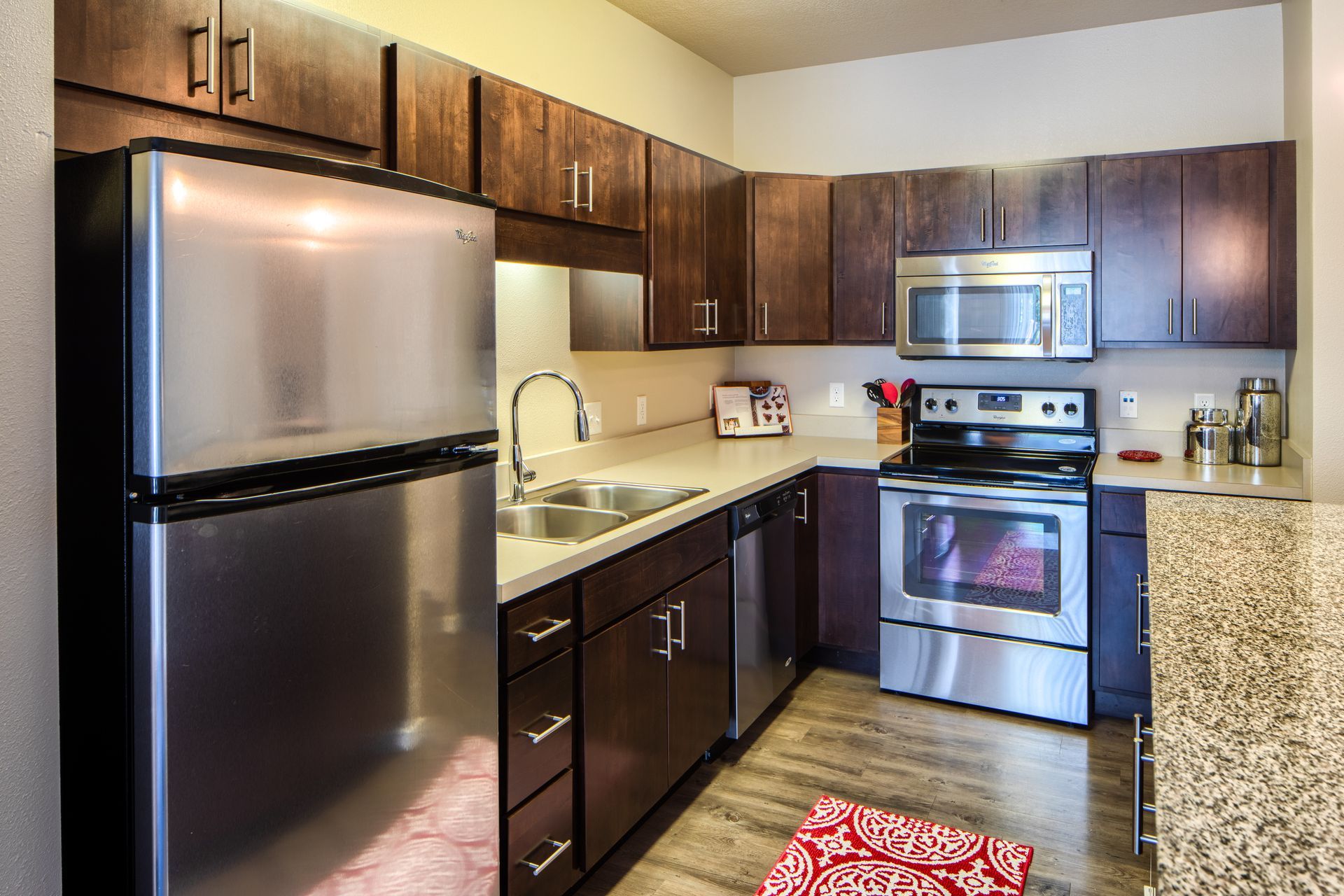 Kitchen with stainless steel appliances, dark wood cabinets, and light countertops.