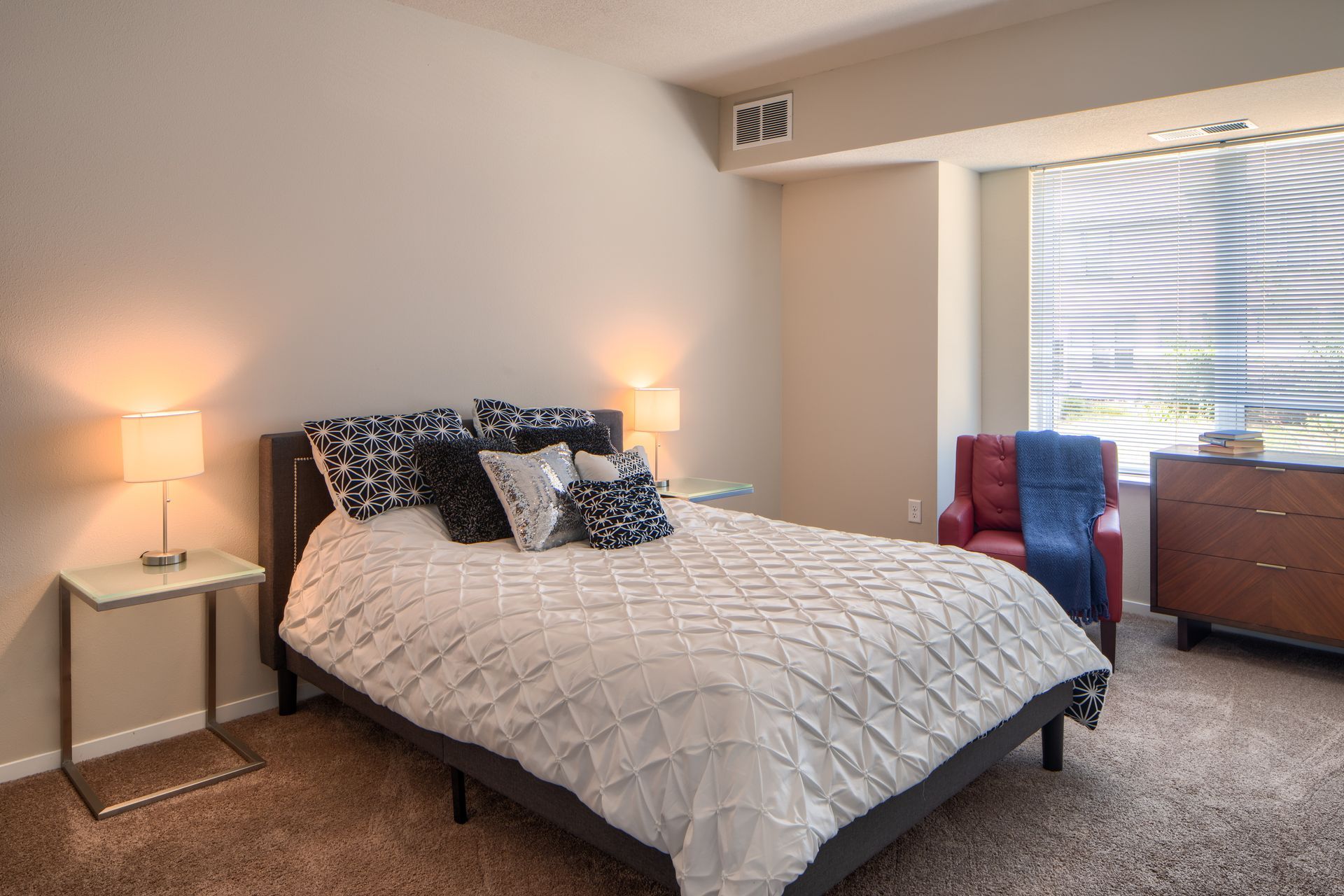 Bedroom with bed, nightstands with lamps, dresser, and armchair.