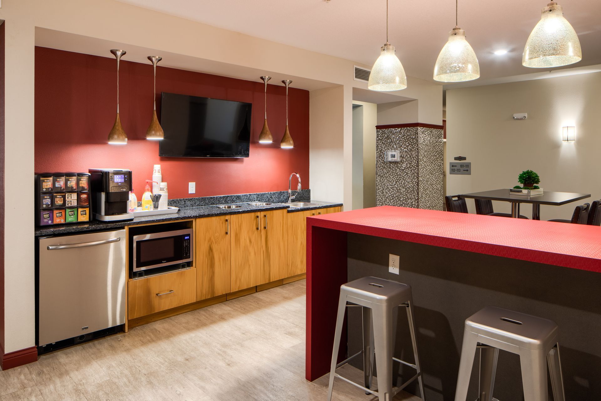 Modern kitchen with appliances, bar, and seating. Red accent wall and countertops.