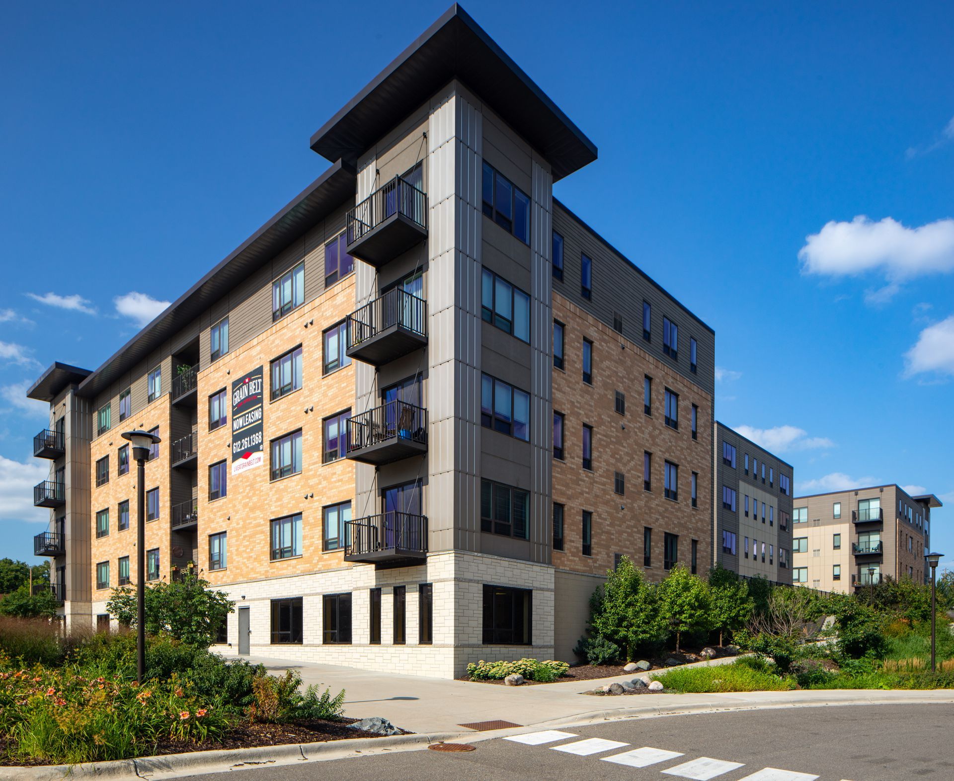 Multi-story brick apartment building with balconies on a sunny day.
