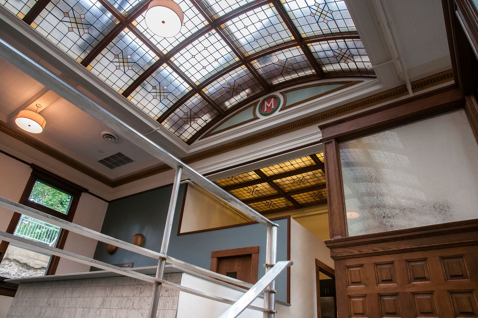 Interior view of a building with a stained glass ceiling and a staircase with a metal railing.