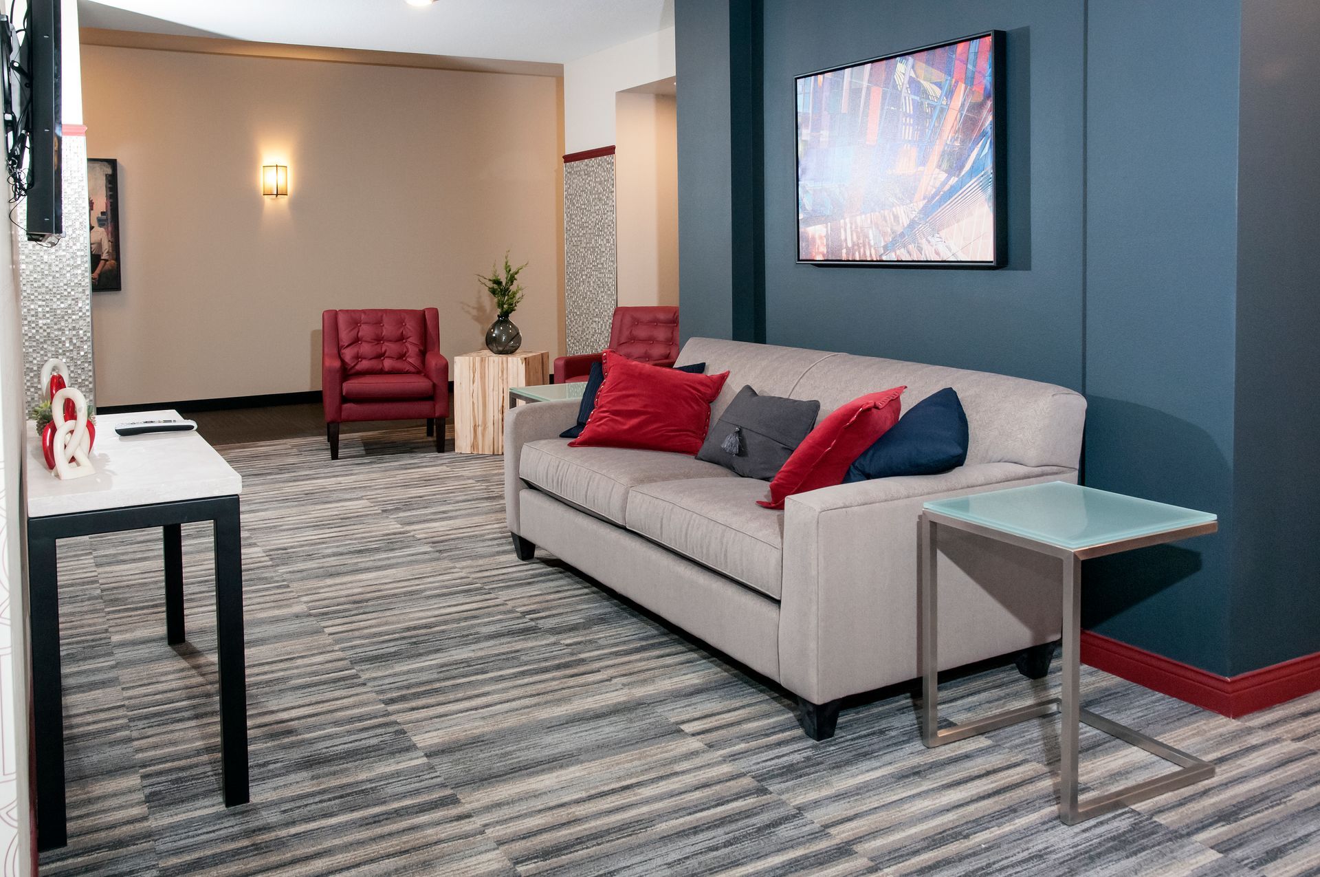 Cozy hotel lounge with sofa, armchairs, and abstract art on blue wall.