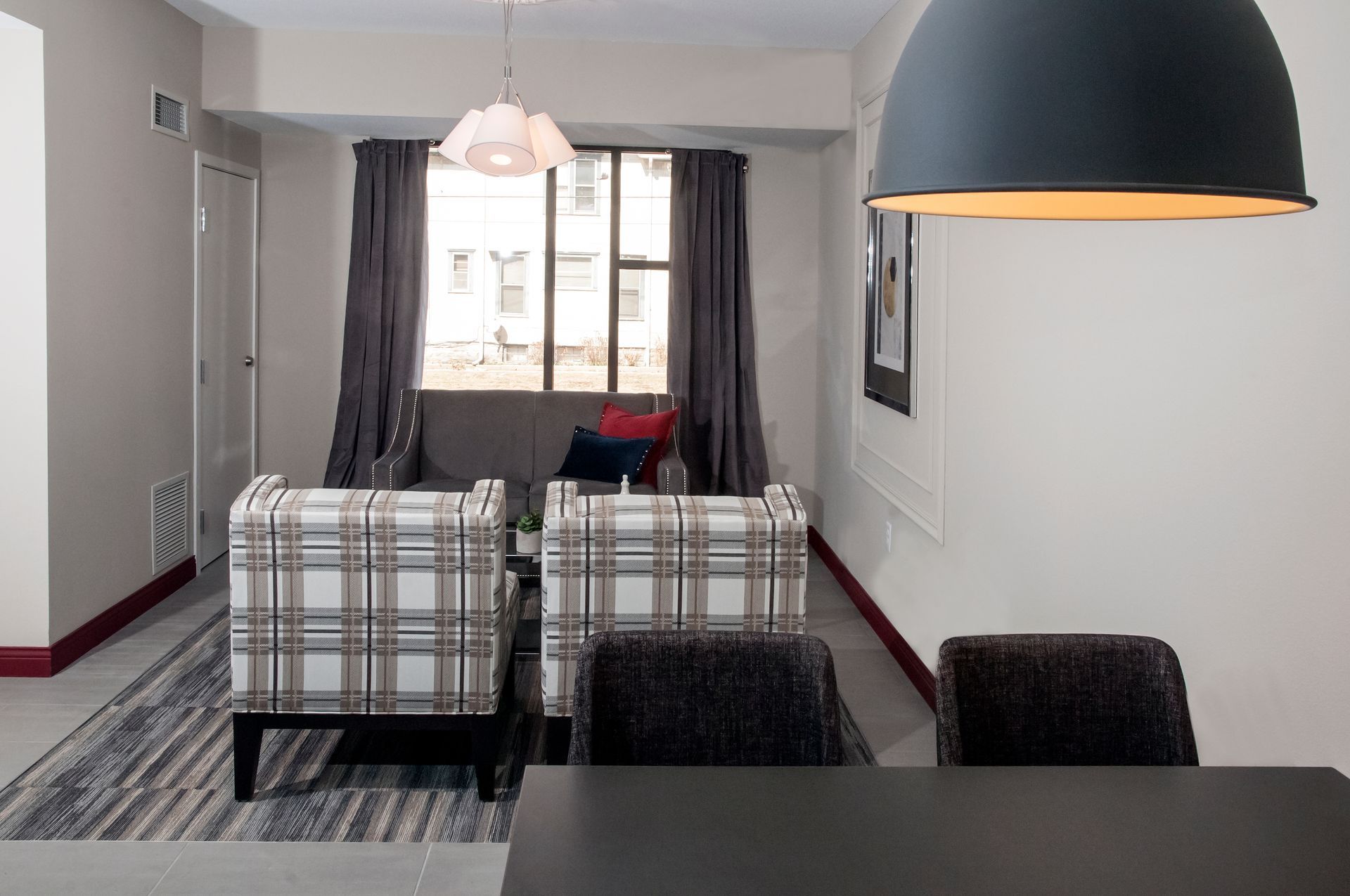 Living room with plaid chairs, a window, and dark gray curtains.