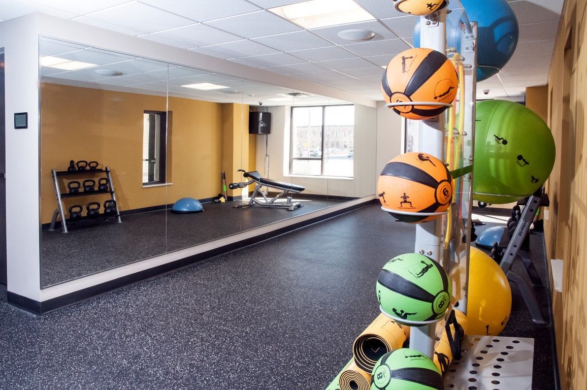 Gym with weights, exercise balls, and mirrors. Dark floor, yellow walls.