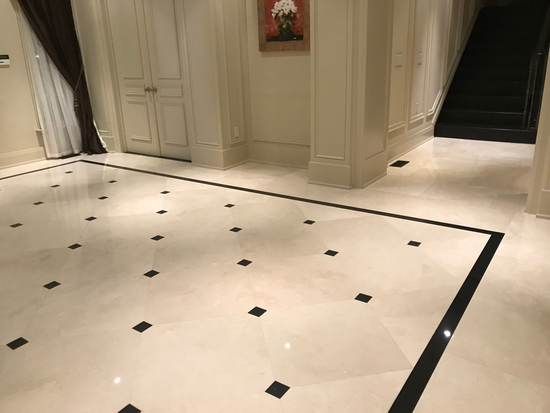 A hallway with a marble floor and black and white tiles.