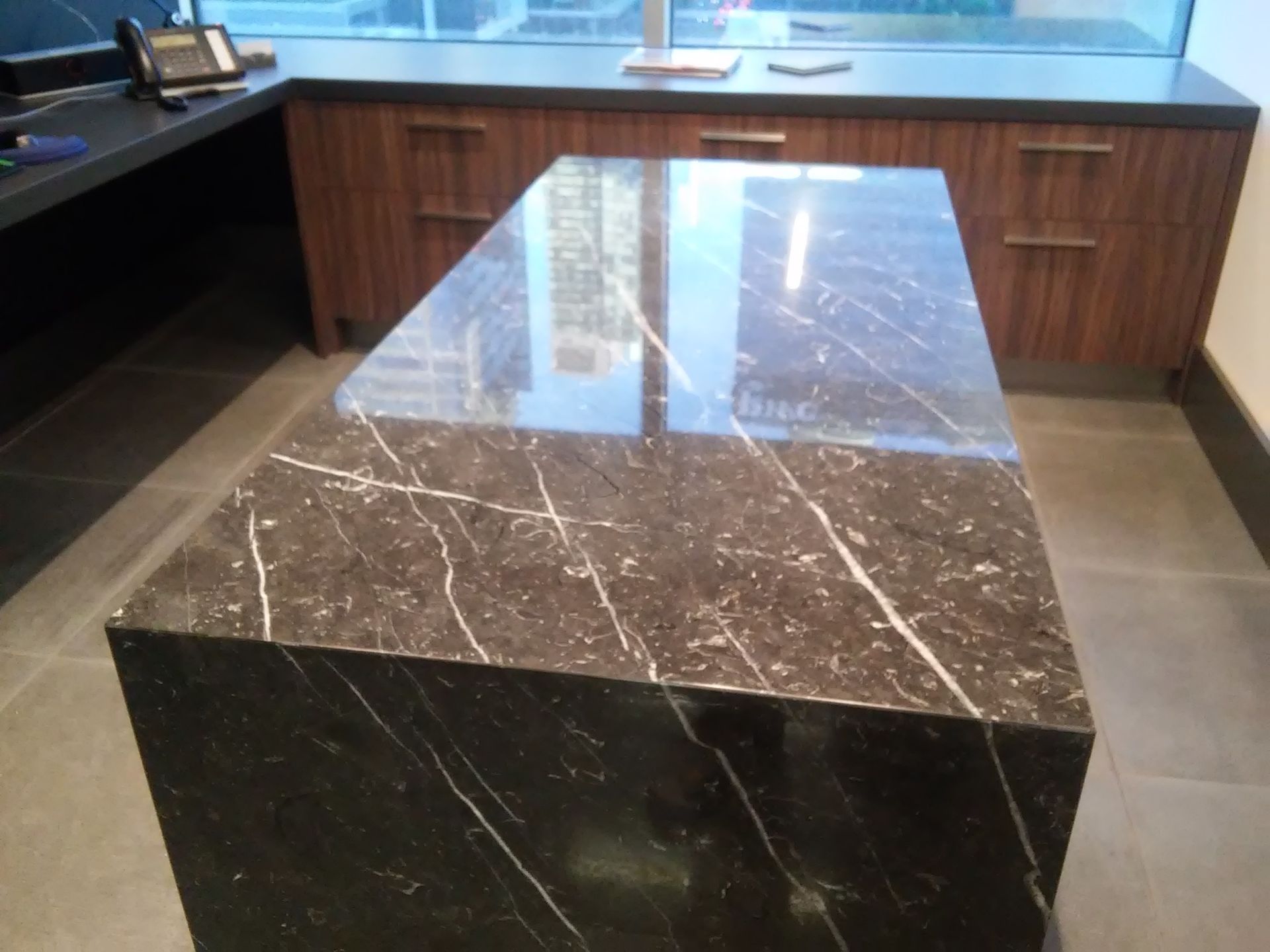 Dark marble countertop with white veining, in a modern office setting.