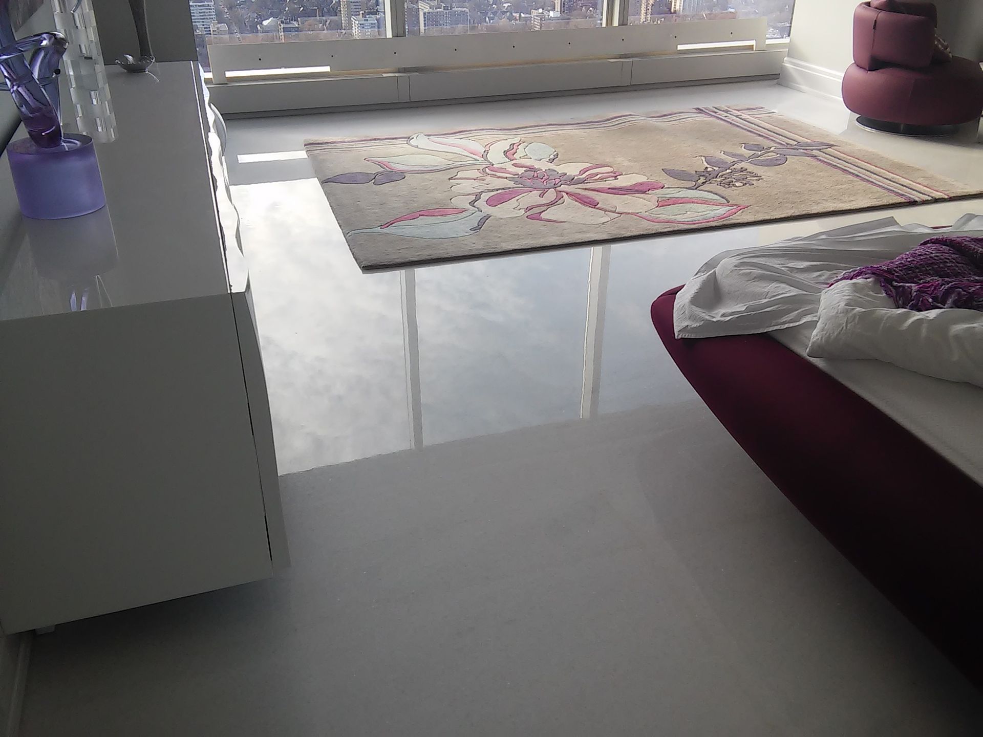 A bedroom with a bed and a rug on the floor