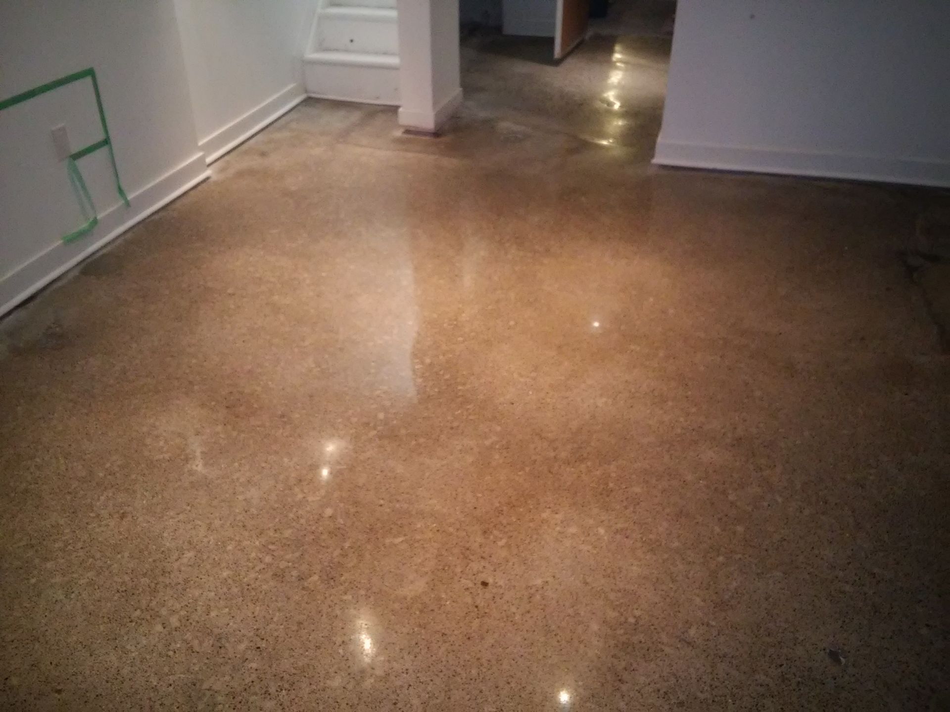 A room with a shiny concrete floor and white walls.