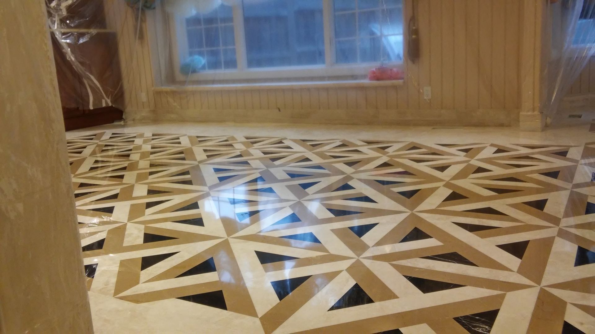 Geometric-patterned wood floor beside a window in a warmly lit room