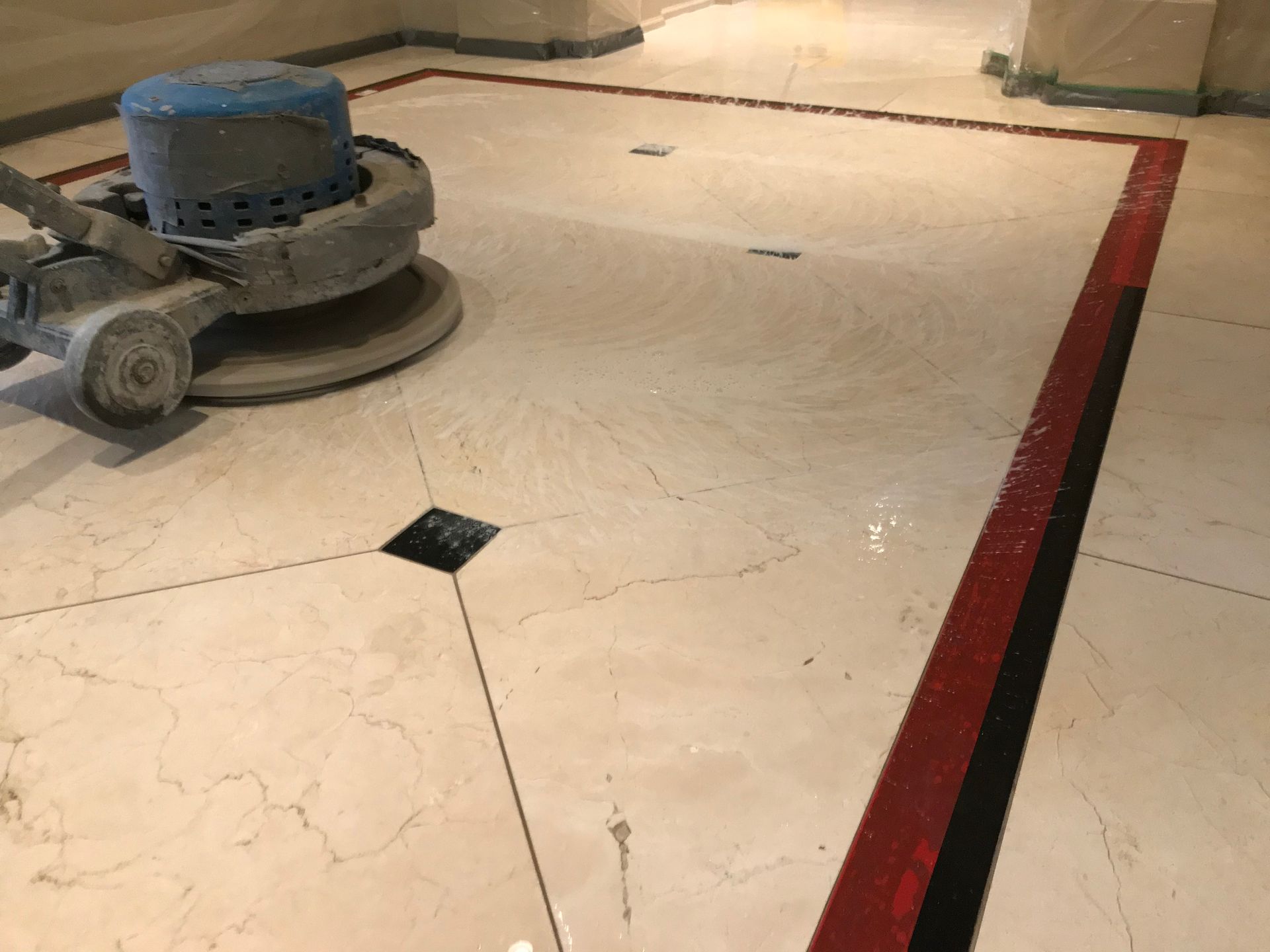 A machine is polishing a marble floor in a hallway.