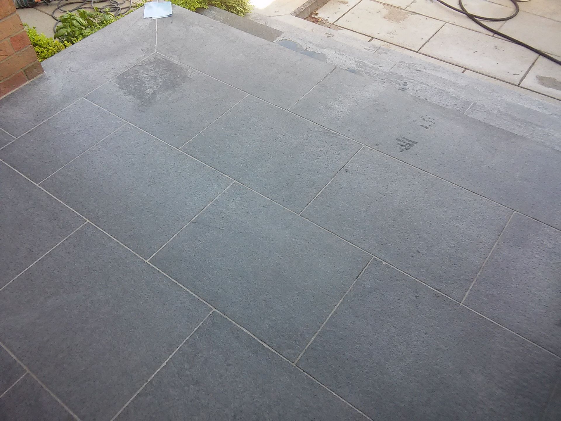 Gray tiled patio with a small wet stain near the top left corner.