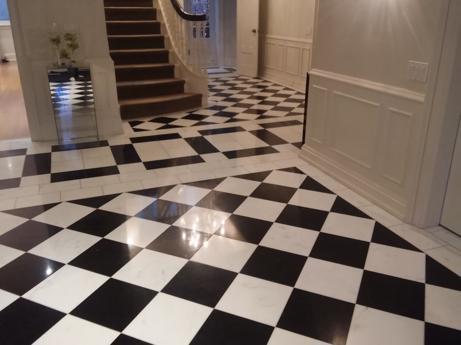 Hallway with black-and-white checkered tile floor and a staircase on the left