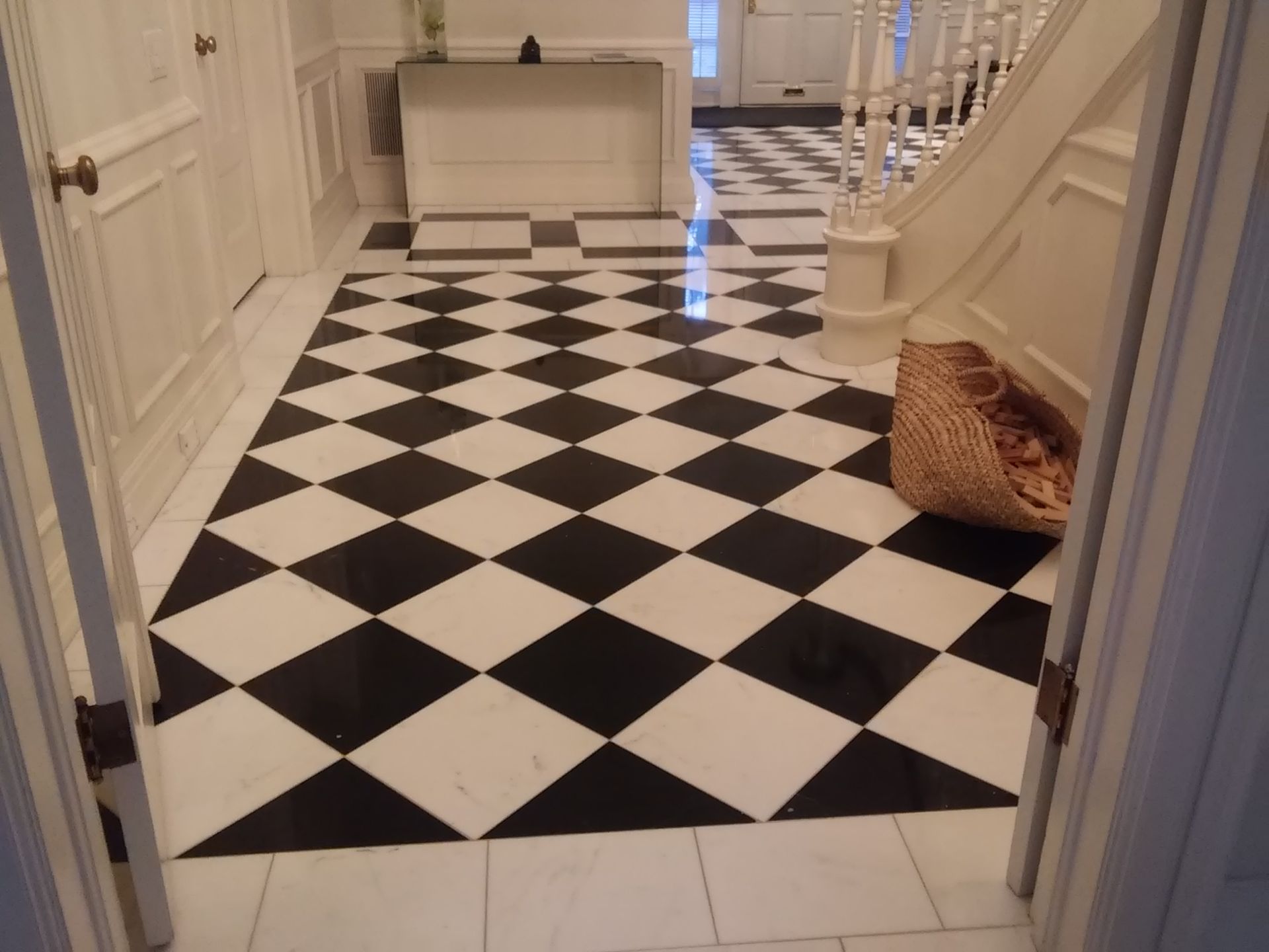 White hallway with black-and-white checkered floor and a wicker basket near the wall