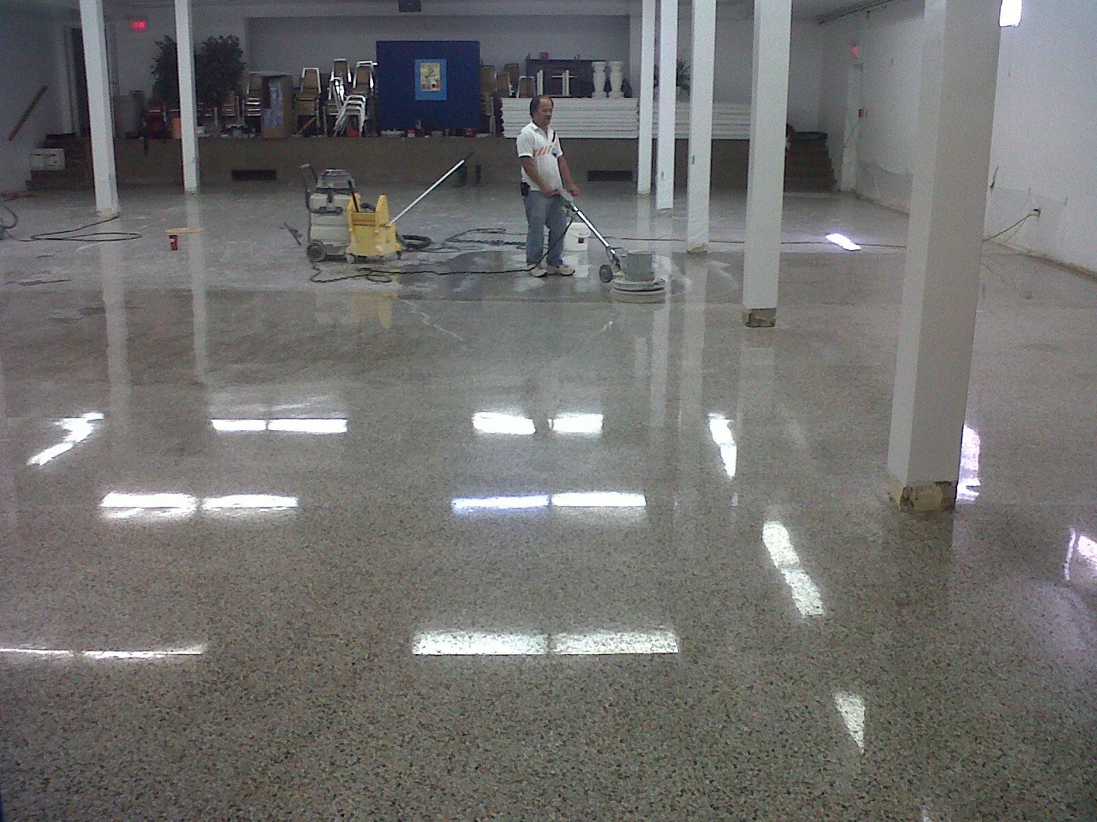 A man is cleaning a shiny floor with a vacuum cleaner