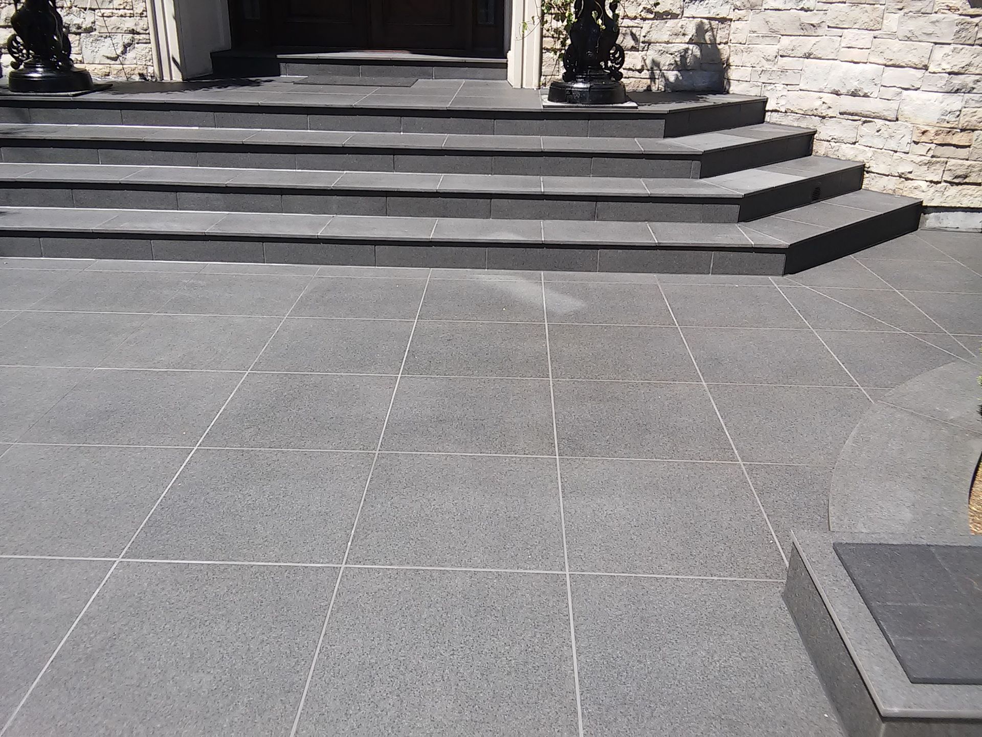 Dark gray tiled patio and steps leading to a building entrance.