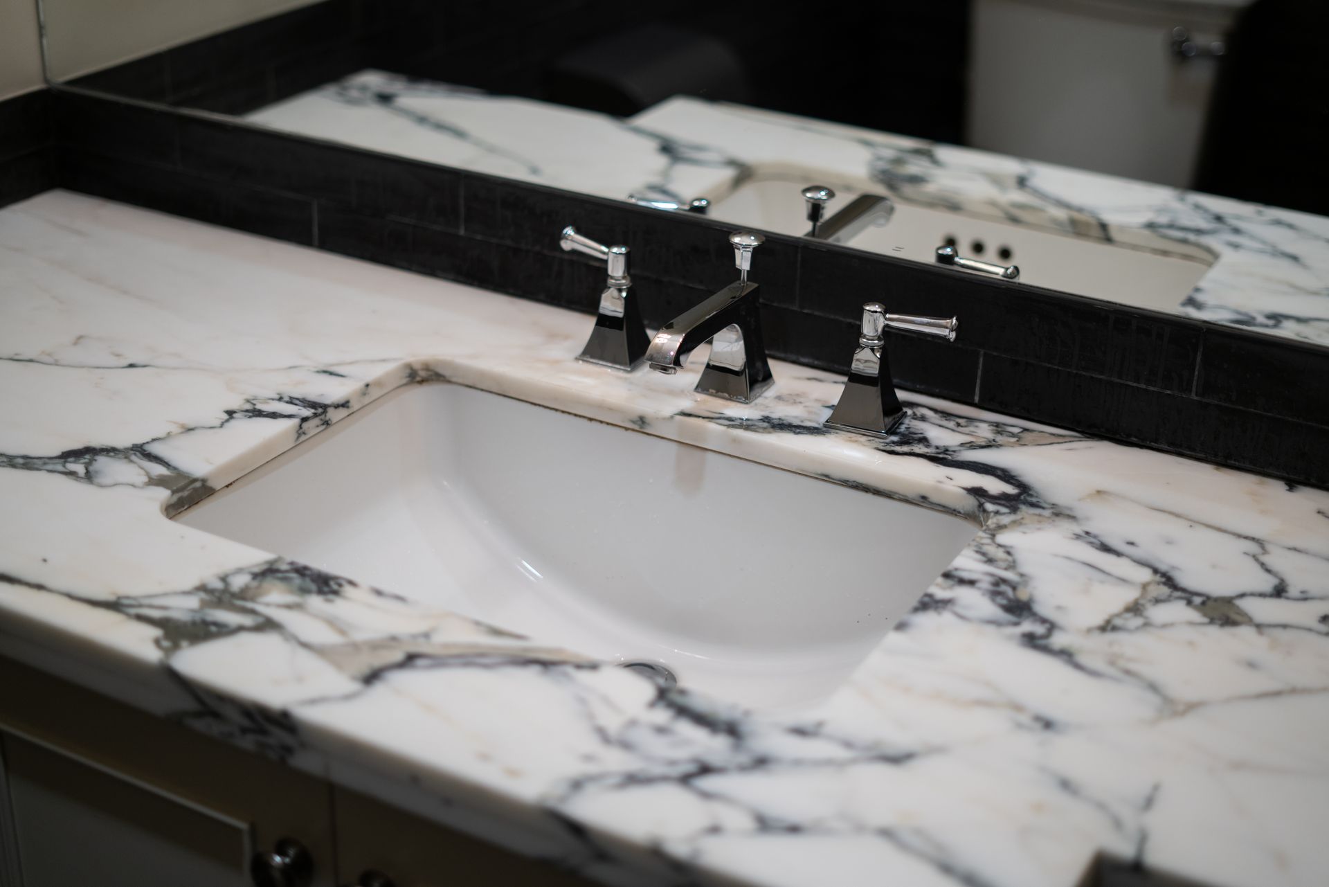 A bathroom sink with a marble counter top and a mirror.
